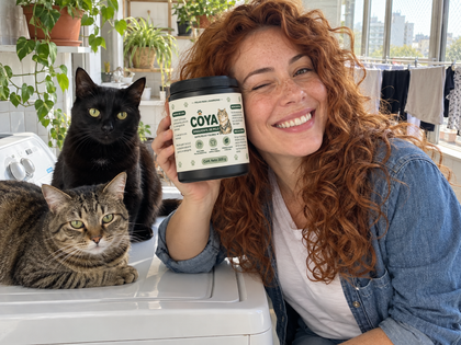 Mujer con dos gatos sobre el lavarropas mostrando el pote de COYA